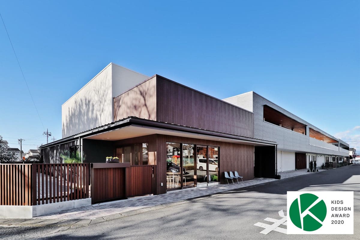 キッズデザイン賞2020を受賞した園舎の外観。焦茶の木板張りと白い壁を組み合わせた低層の建物