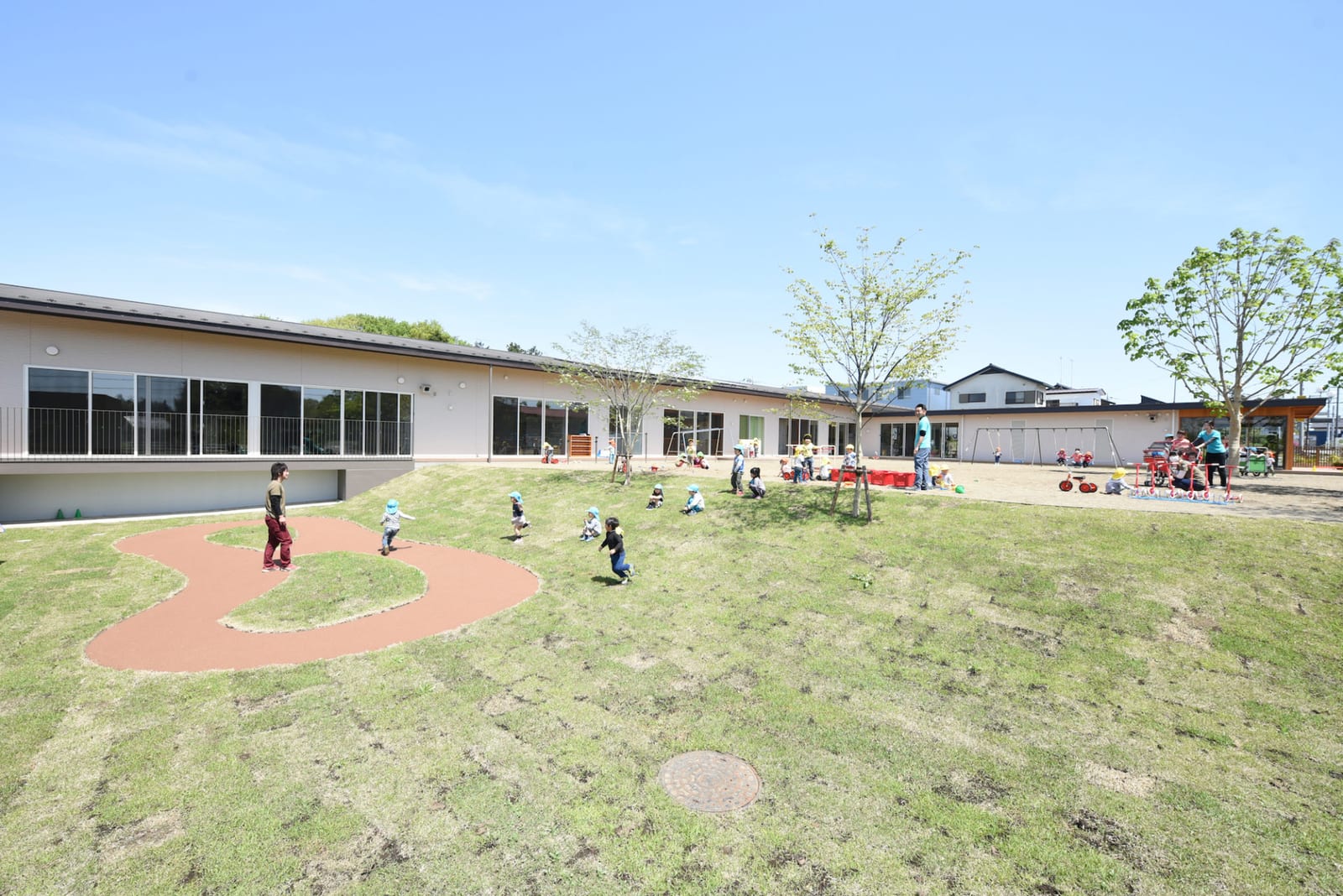 大地の恵みのなーさりぃの起伏のある園庭で遊ぶ子どもたち